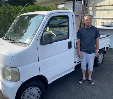 軽トラックとその横に立っている男性の写真