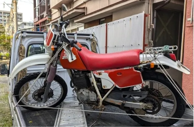 軽トラックに積まれた赤と白のオフロードバイクの側面写真